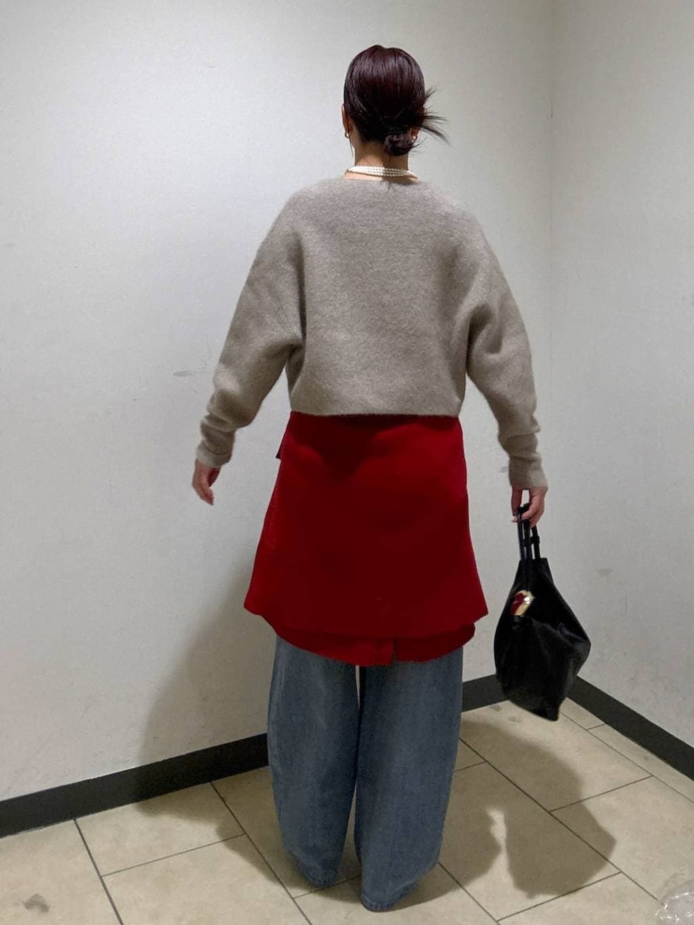 ベージュ系のニット/セーター、レッド系のカーディガン/ボレロ、ブルー系のデニムパンツを着用したレディースの冬コーディネートの4枚目の写真