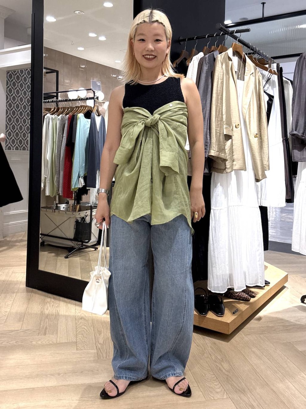 ホワイト系のショルダーバッグ、ブルー系のデニムパンツ、ブラック系のサンダルを着用したレディースの夏コーディネートの6枚目の写真