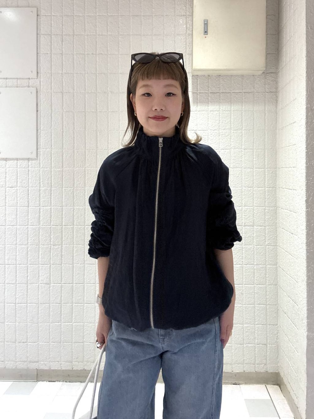 ブルー系のデニムパンツ、ホワイト系のショルダーバッグ、ブルー系のブルゾンを着用したレディースの春コーディネートの6枚目の写真