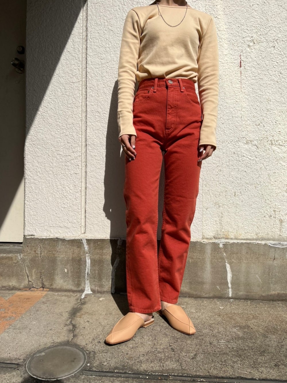 レッド系のデニムパンツ、ベージュ系のTシャツ/カットソー、ベージュ系のその他シューズを着用したレディースの冬コーディネートの3枚目の写真