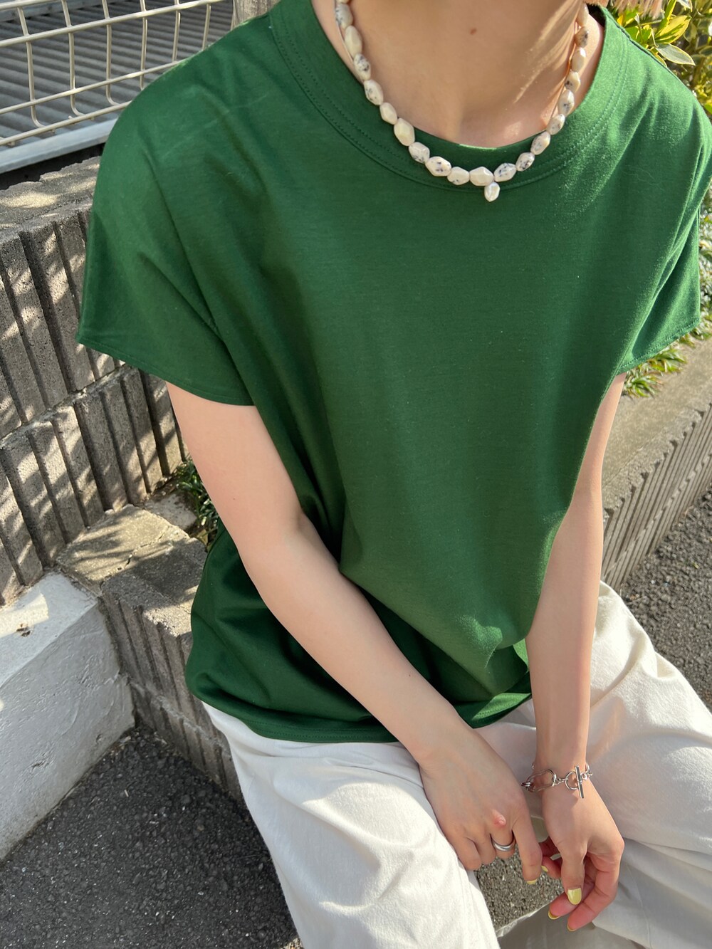 グリーン系のTシャツ/カットソー、ブラック系のサンダル、ホワイト系のその他パンツを着用したレディースの春コーディネートの2枚目の写真