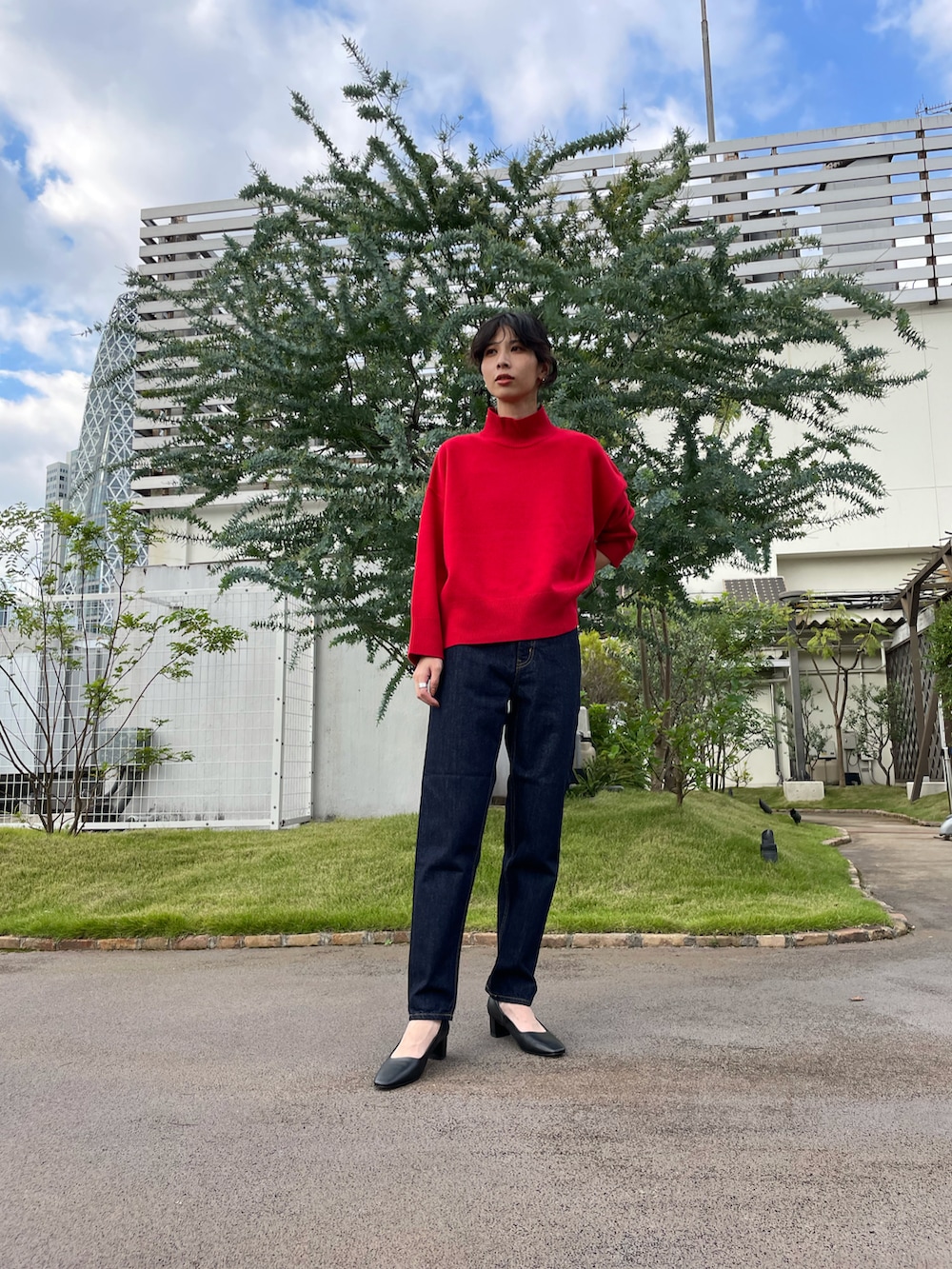 レッド系のニット/セーター、ブルー系のデニムパンツを着用したレディースの秋コーディネートの2枚目の写真