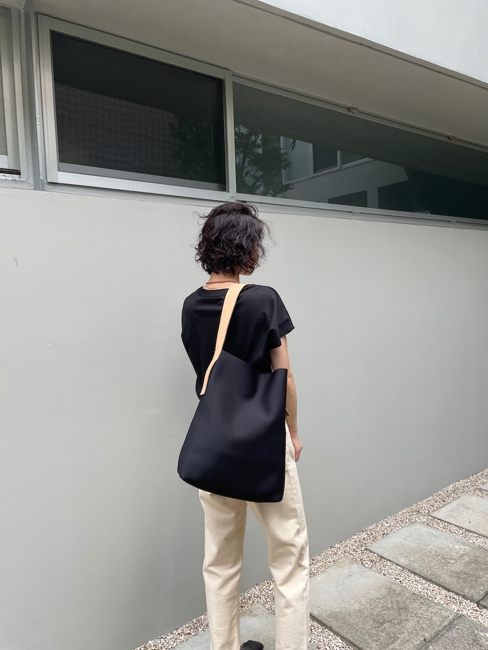 ブラック系のTシャツ/カットソー、ホワイト系のデニムパンツ、ブラック系のサンダルを着用したレディースの夏コーディネートの2枚目の写真