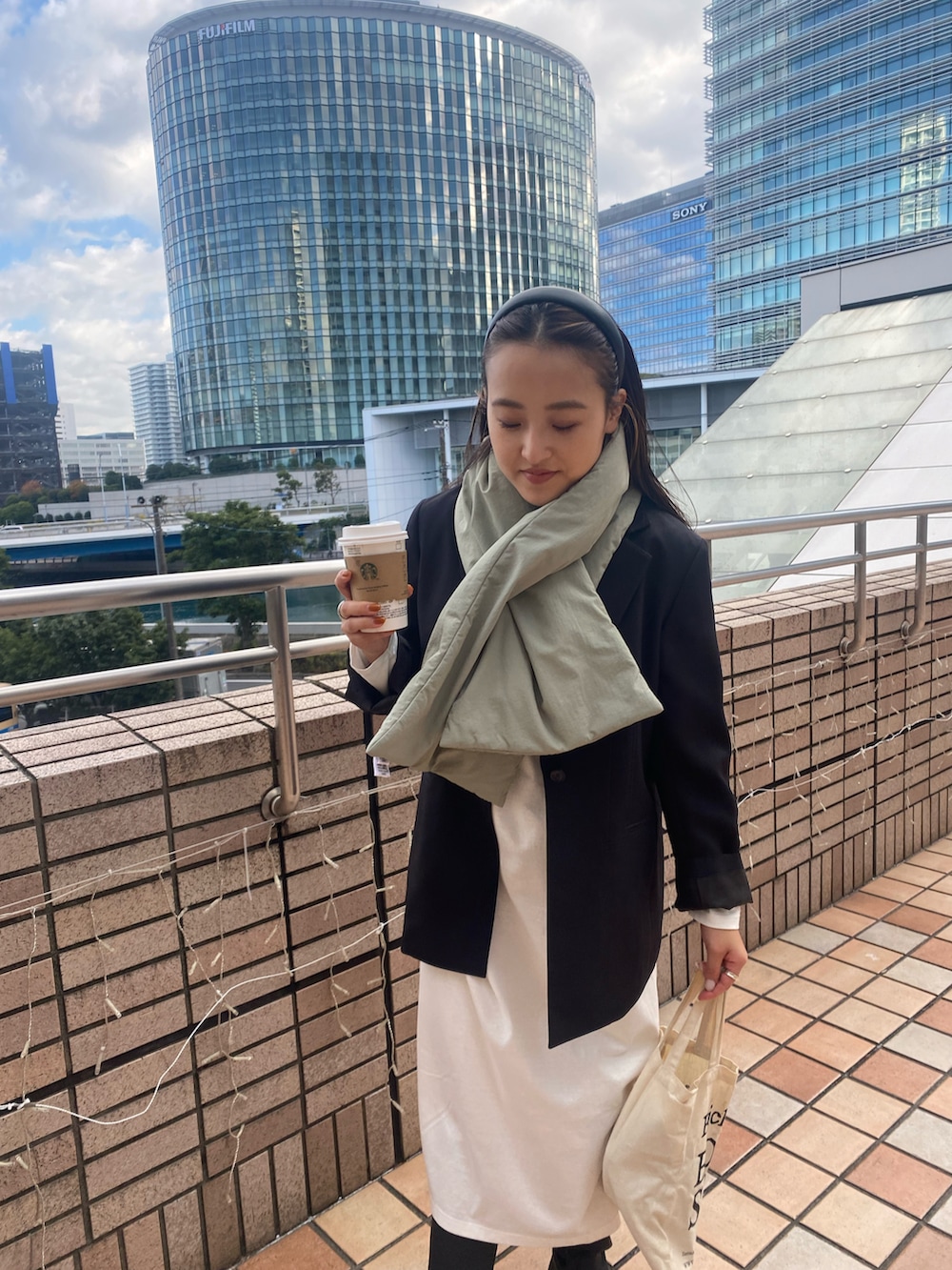 ホワイト系のワンピース、ブラック系のテーラードジャケット、グリーン系のネックウォーマー/スヌードを着用したレディースの冬コーディネートの2枚目の写真