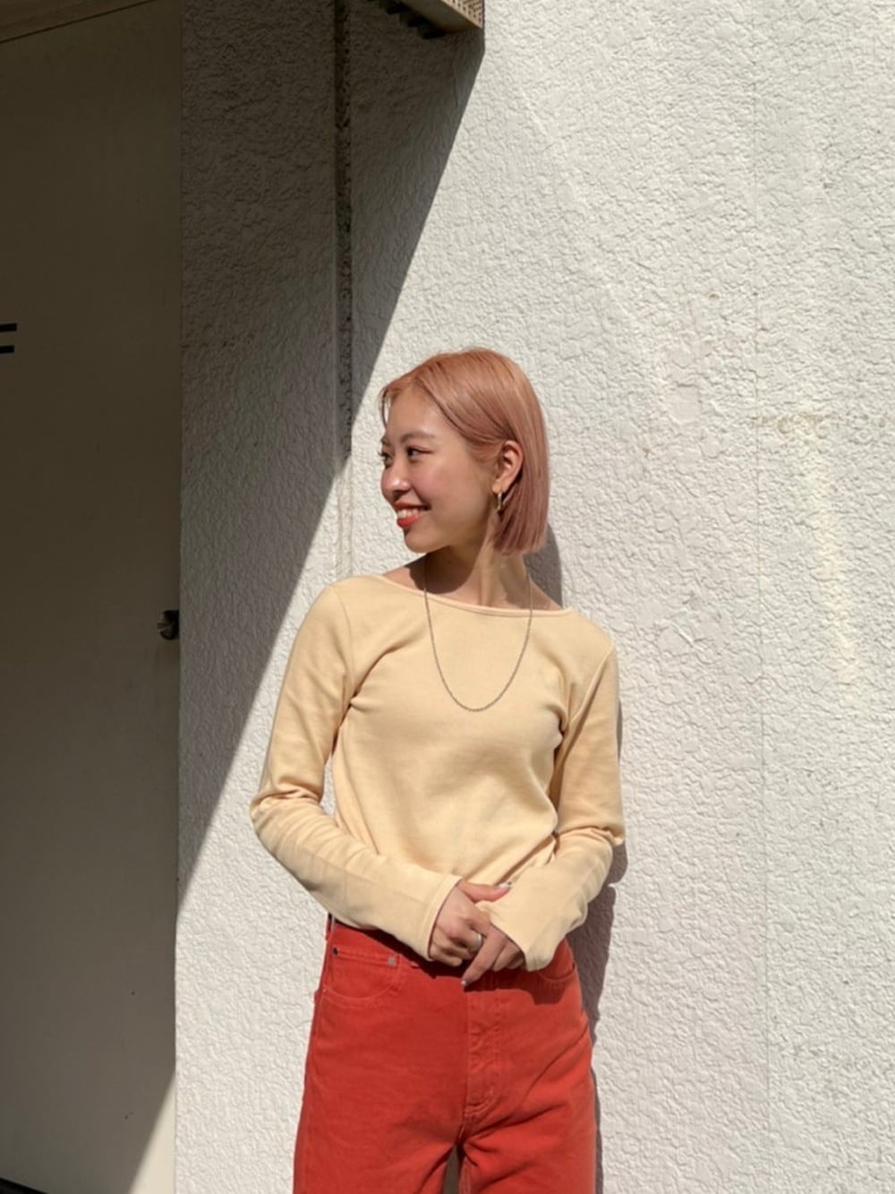 レッド系のデニムパンツ、ベージュ系のTシャツ/カットソー、ベージュ系のその他シューズを着用したレディースの冬コーディネートの2枚目の写真