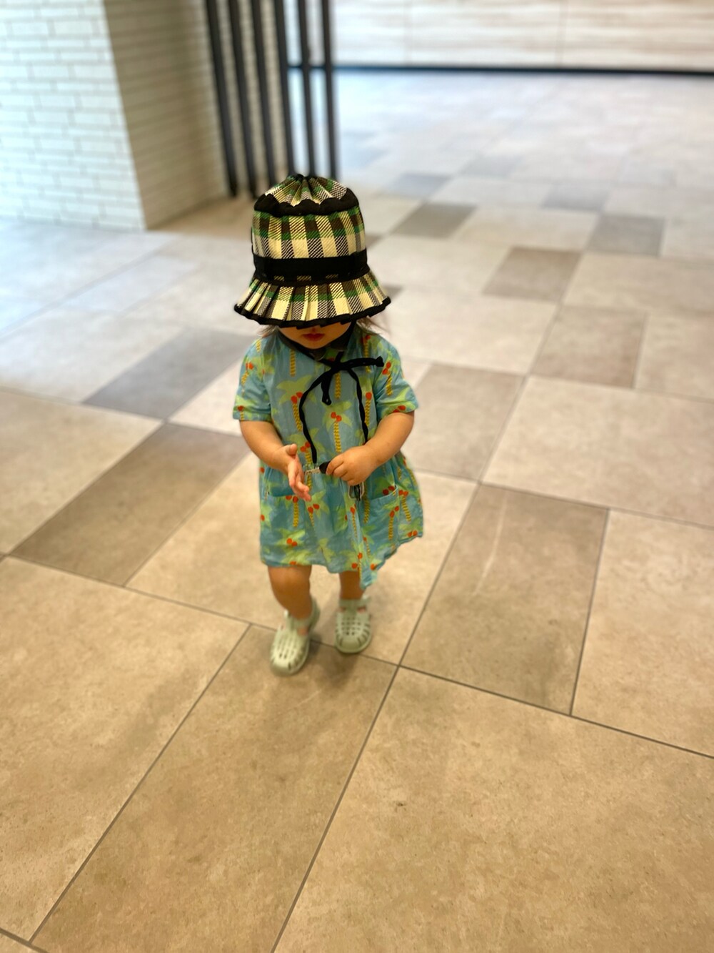 ブルー系のサンダル、ブルー系のワンピース、グリーン系のハットを着用したキッズの夏コーディネートの3枚目の写真