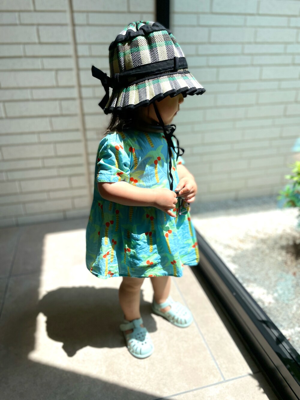 ブルー系のサンダル、ブルー系のワンピース、グリーン系のハットを着用したキッズの夏コーディネートの2枚目の写真