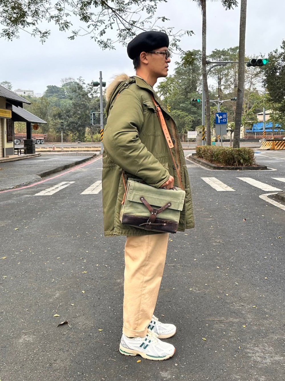 グリーン系のミリタリージャケット、ホワイト系のスニーカー、ブラック系のハンチング/ベレー帽を着用したメンズの冬コーディネートの2枚目の写真