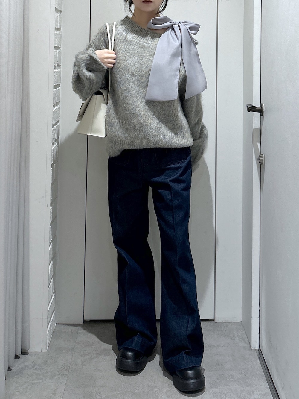 グレー系のニット/セーター、ブルー系のデニムパンツ、ホワイト系のショルダーバッグを着用したレディースの冬コーディネートの5枚目の写真