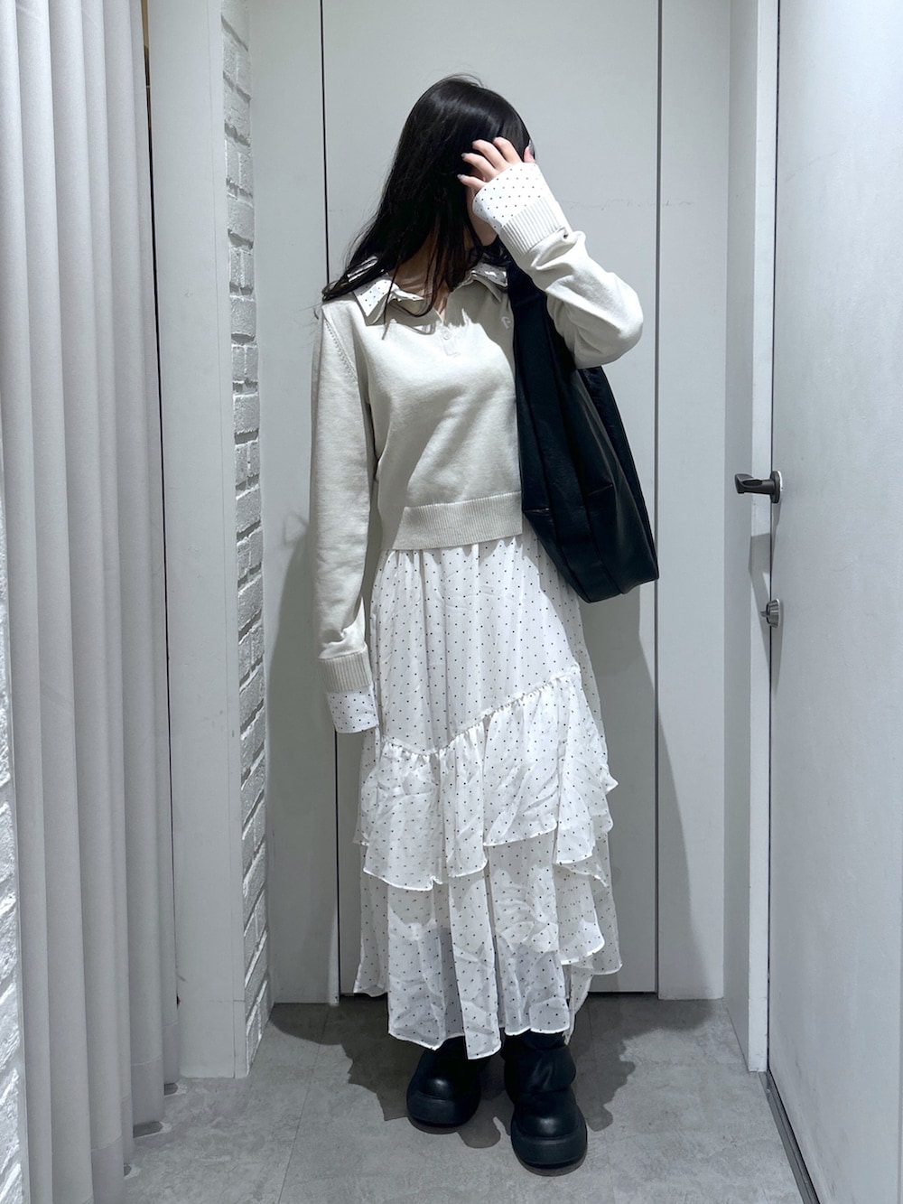 ブラック系のトートバッグ、ホワイト系のスカート、ベージュ系のニット/セーターを着用したレディースの春コーディネートの3枚目の写真