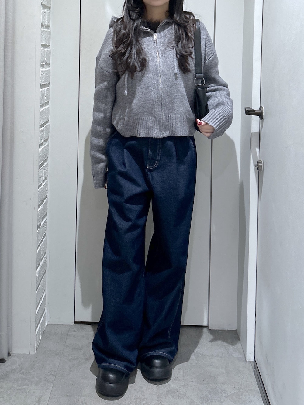グレー系のニット/セーター、ブルー系のその他パンツ、ブラック系のショルダーバッグを着用したレディースの冬コーディネートの2枚目の写真