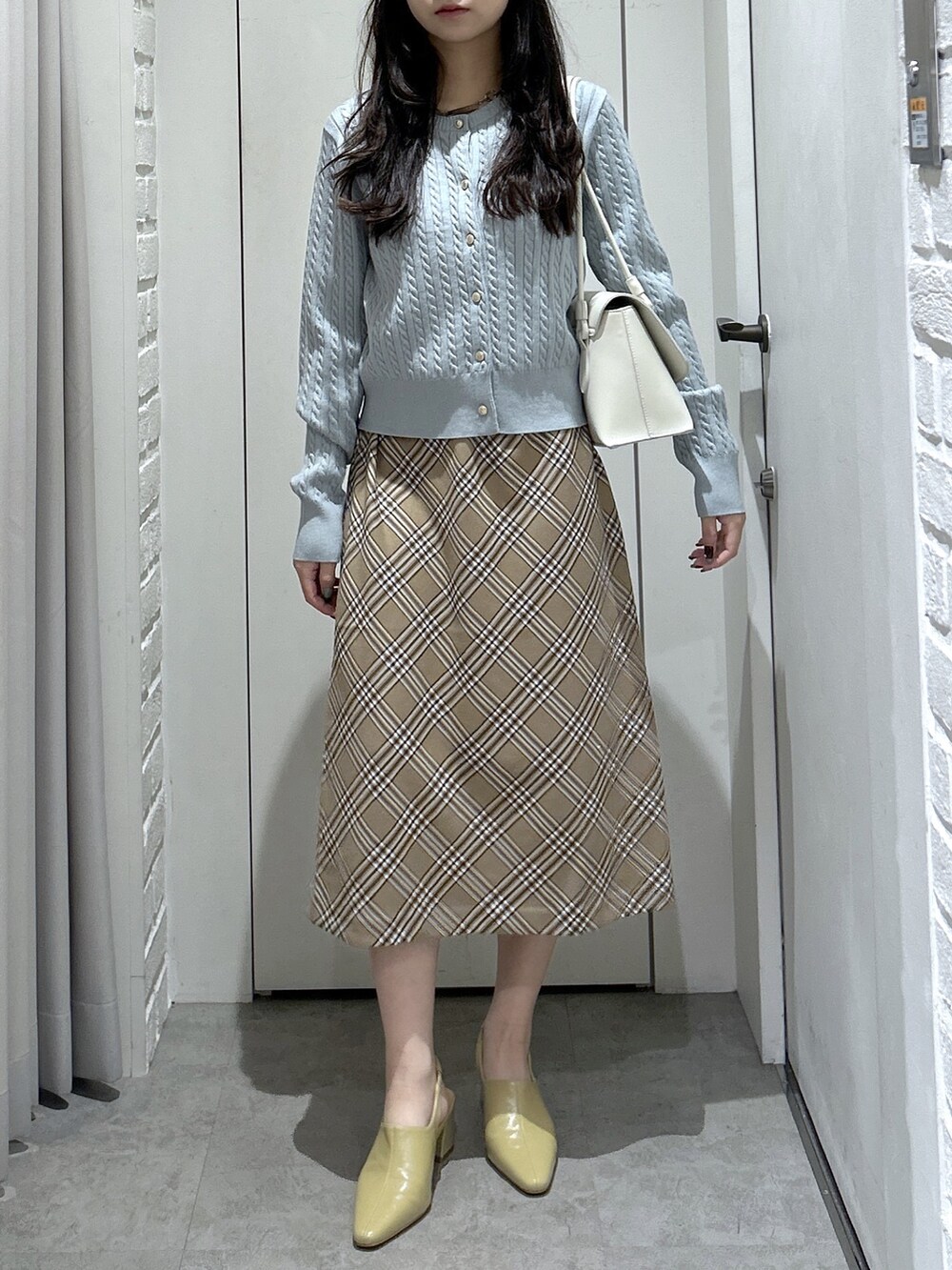ブルー系のカーディガン/ボレロ、ベージュ系のスカート、ホワイト系のトートバッグを着用したレディースの秋コーディネートの2枚目の写真