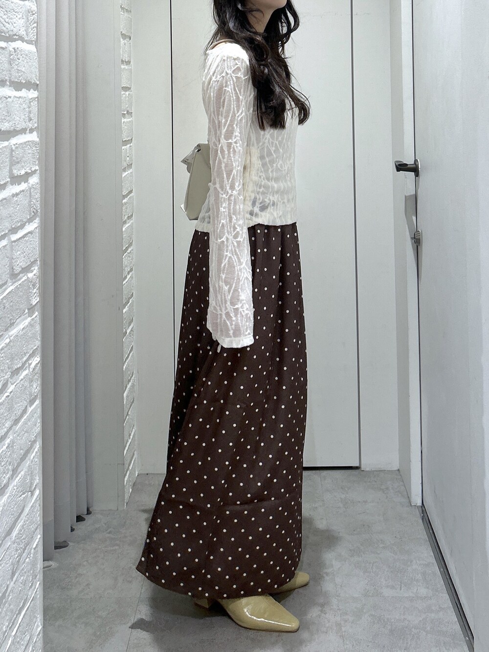 ホワイト系のショルダーバッグ、ホワイト系のTシャツ/カットソー、ベージュ系のパンプスを着用したレディースの秋コーディネートの4枚目の写真