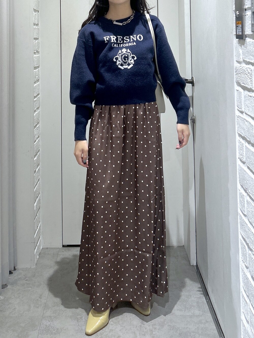 ブルー系のニット/セーター、ホワイト系のショルダーバッグ、ベージュ系のパンプスを着用したレディースの秋コーディネートの3枚目の写真