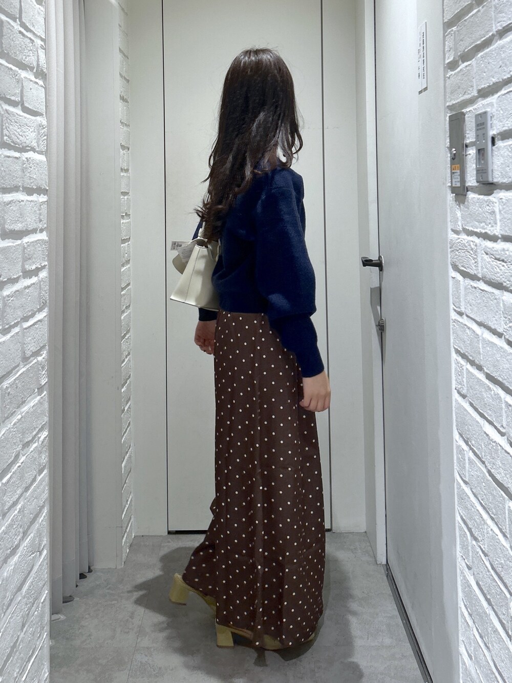 ブルー系のニット/セーター、ホワイト系のショルダーバッグ、ベージュ系のパンプスを着用したレディースの秋コーディネートの4枚目の写真