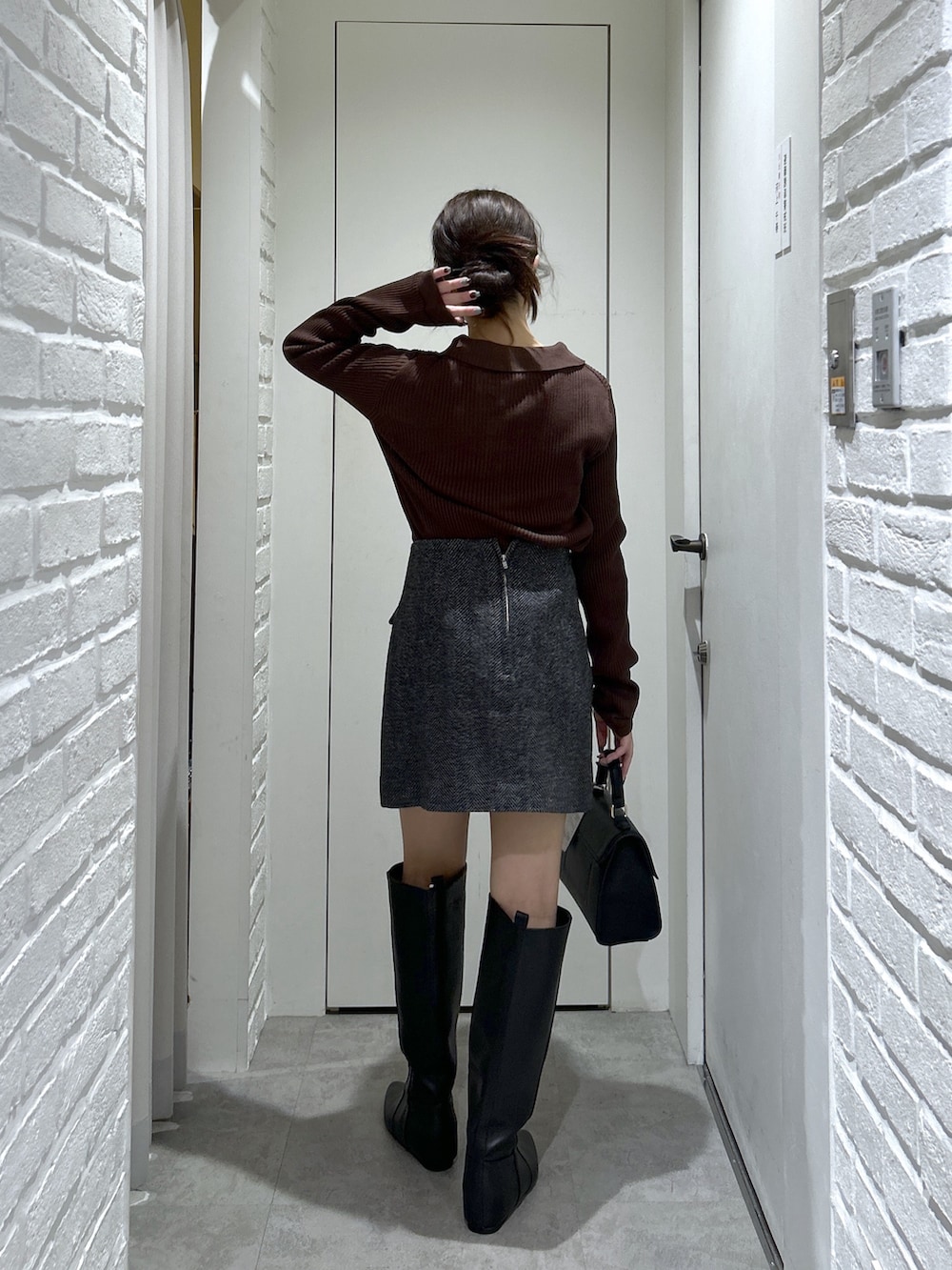 ブラウン系のニット/セーター、ブラック系のスカート、ブラック系のブーツを着用したレディースの秋コーディネートの5枚目の写真