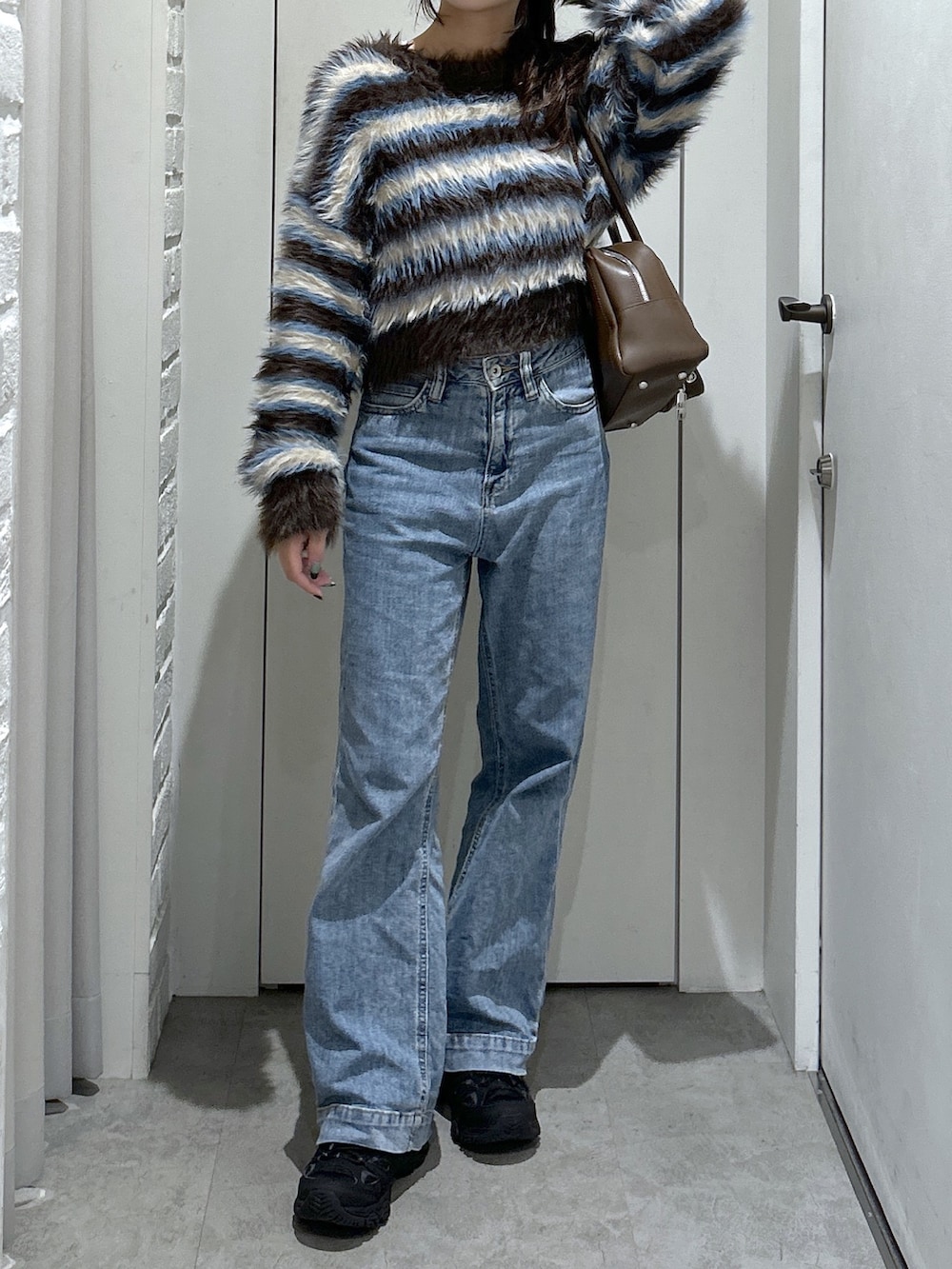 ブルー系のデニムパンツ、ブラウン系のトートバッグ、ブラウン系のニット/セーターを着用したレディースの秋コーディネートの3枚目の写真