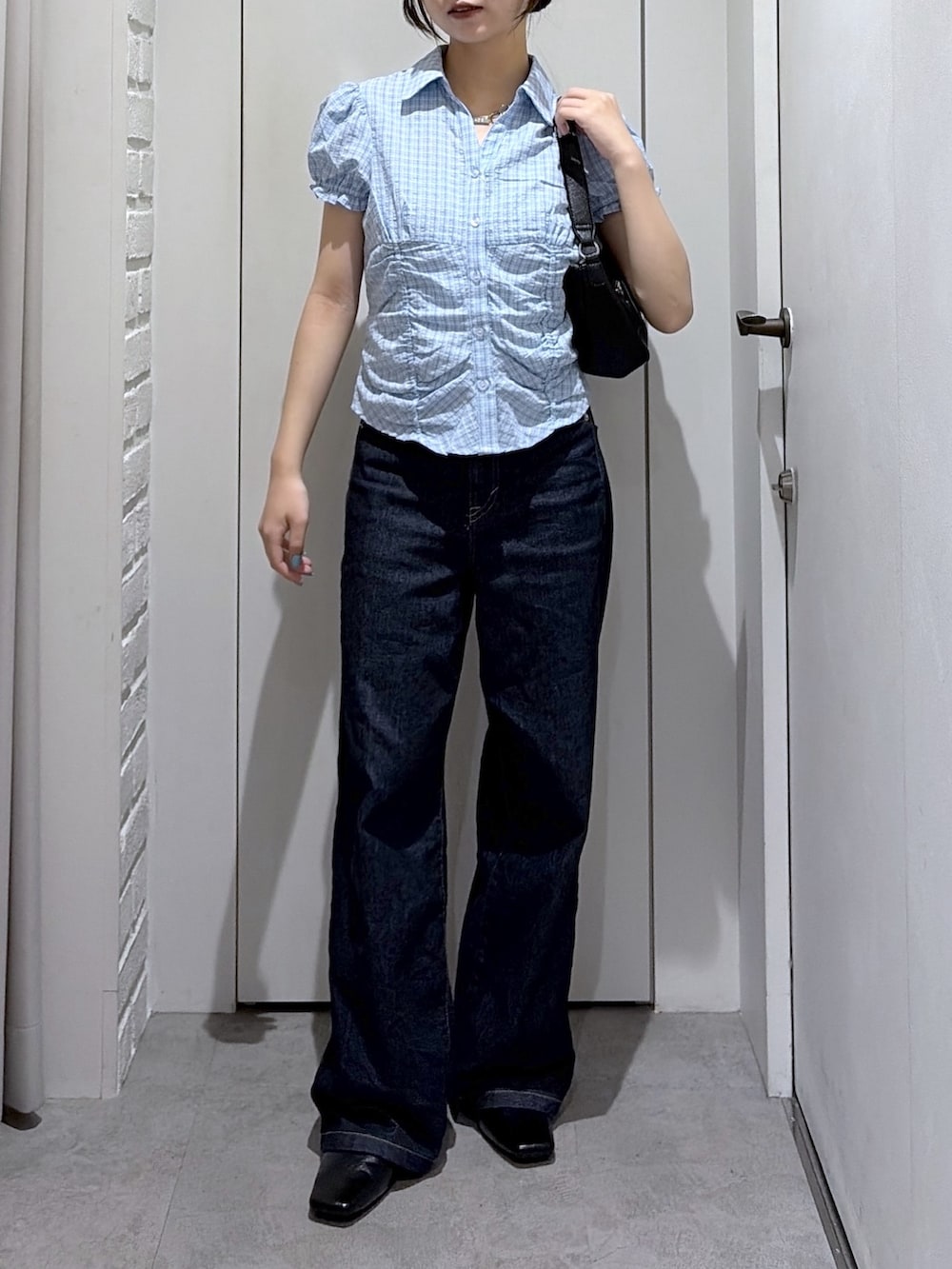 ブルー系のデニムパンツ、ブルー系のシャツ/ブラウス、ブラック系のショルダーバッグを着用したレディースの夏コーディネートの4枚目の写真