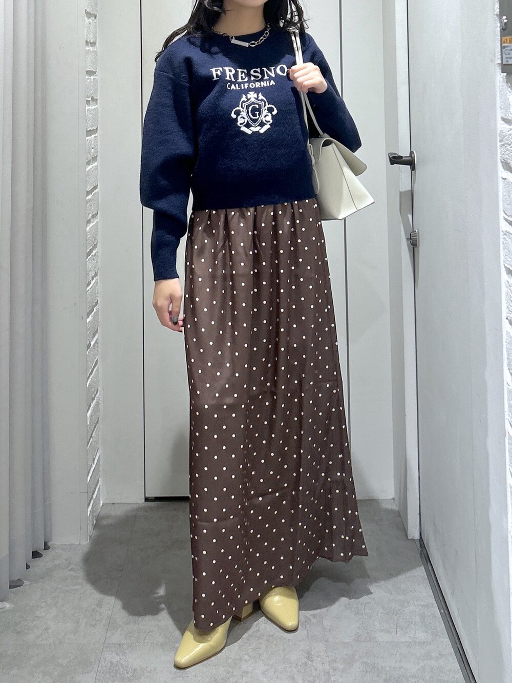 ブルー系のニット/セーター、ホワイト系のショルダーバッグ、ベージュ系のパンプスを着用したレディースの秋コーディネートの2枚目の写真