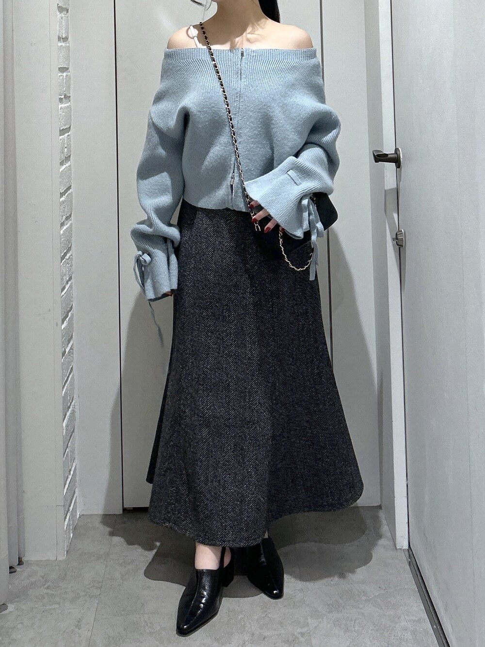 ブルー系のニット/セーター、ブラック系のスカート、ブラック系のパンプスを着用したレディースの冬コーディネートの2枚目の写真