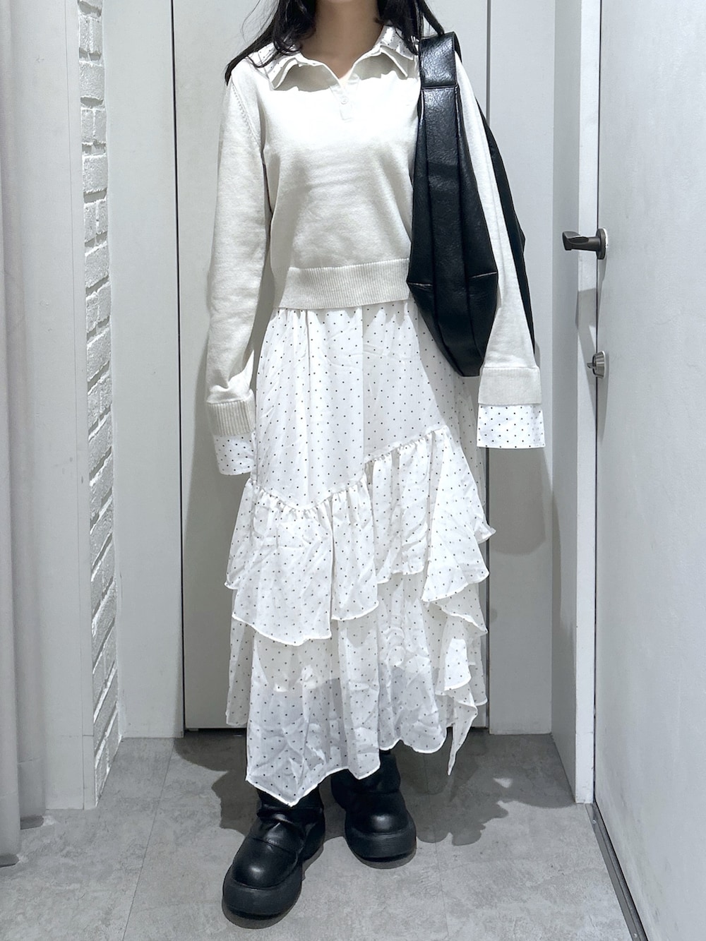 ブラック系のトートバッグ、ホワイト系のスカート、ベージュ系のニット/セーターを着用したレディースの春コーディネートの2枚目の写真
