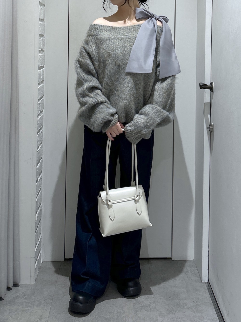 グレー系のニット/セーター、ブルー系のデニムパンツ、ホワイト系のショルダーバッグを着用したレディースの冬コーディネートの6枚目の写真