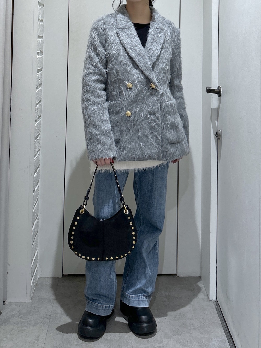 ブルー系のデニムパンツ、ホワイト系のニット/セーター、ブラック系のショルダーバッグを着用したレディースの冬コーディネートの3枚目の写真