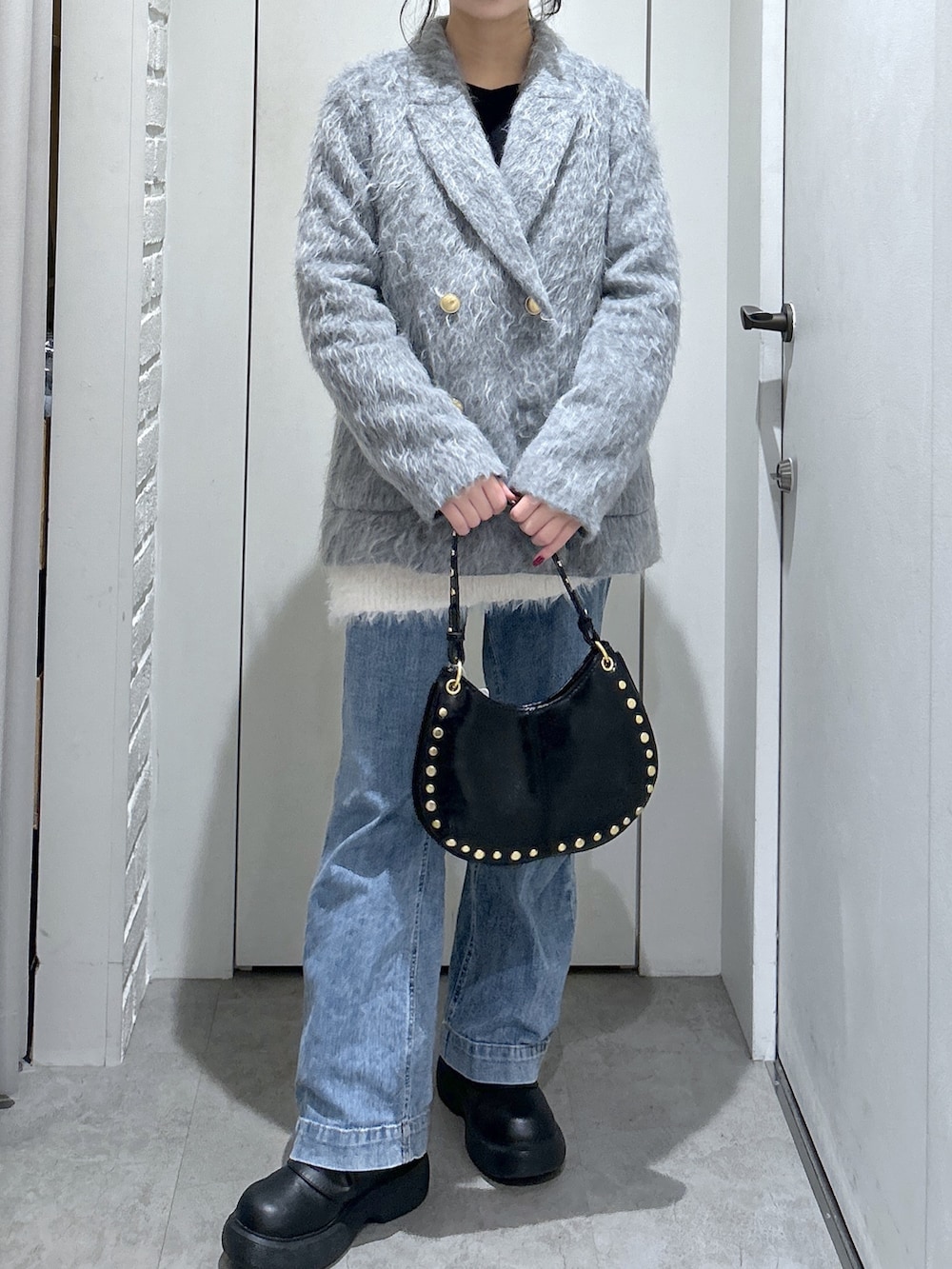 ブルー系のデニムパンツ、ホワイト系のニット/セーター、ブラック系のショルダーバッグを着用したレディースの冬コーディネートの4枚目の写真