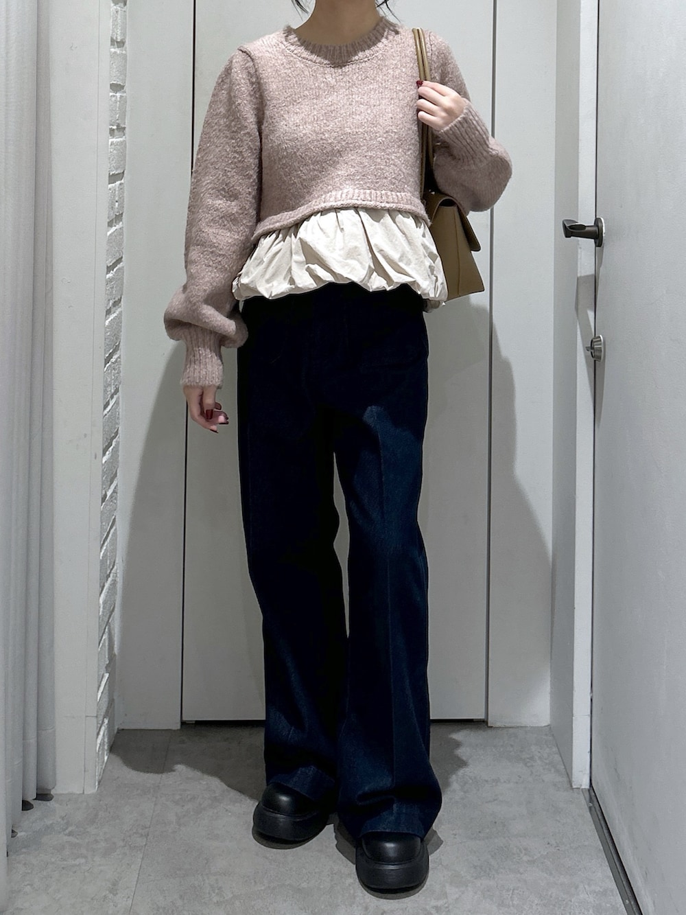 ブルー系のデニムパンツ、ベージュ系のニット/セーター、ベージュ系のショルダーバッグを着用したレディースの冬コーディネートの3枚目の写真