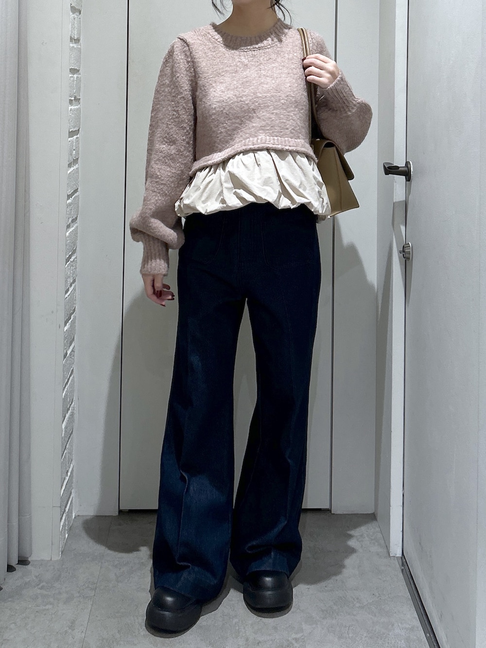 ブルー系のデニムパンツ、ベージュ系のニット/セーター、ベージュ系のショルダーバッグを着用したレディースの冬コーディネートの2枚目の写真