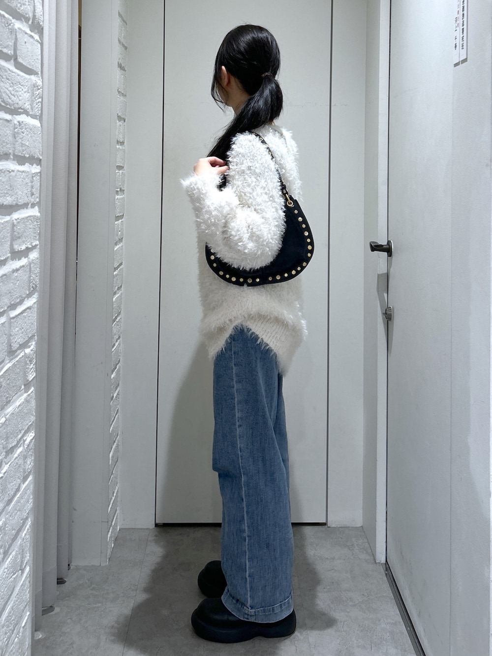 ホワイト系のニット/セーター、ブラック系のショルダーバッグ、ブルー系のデニムパンツを着用したレディースの冬コーディネートの5枚目の写真