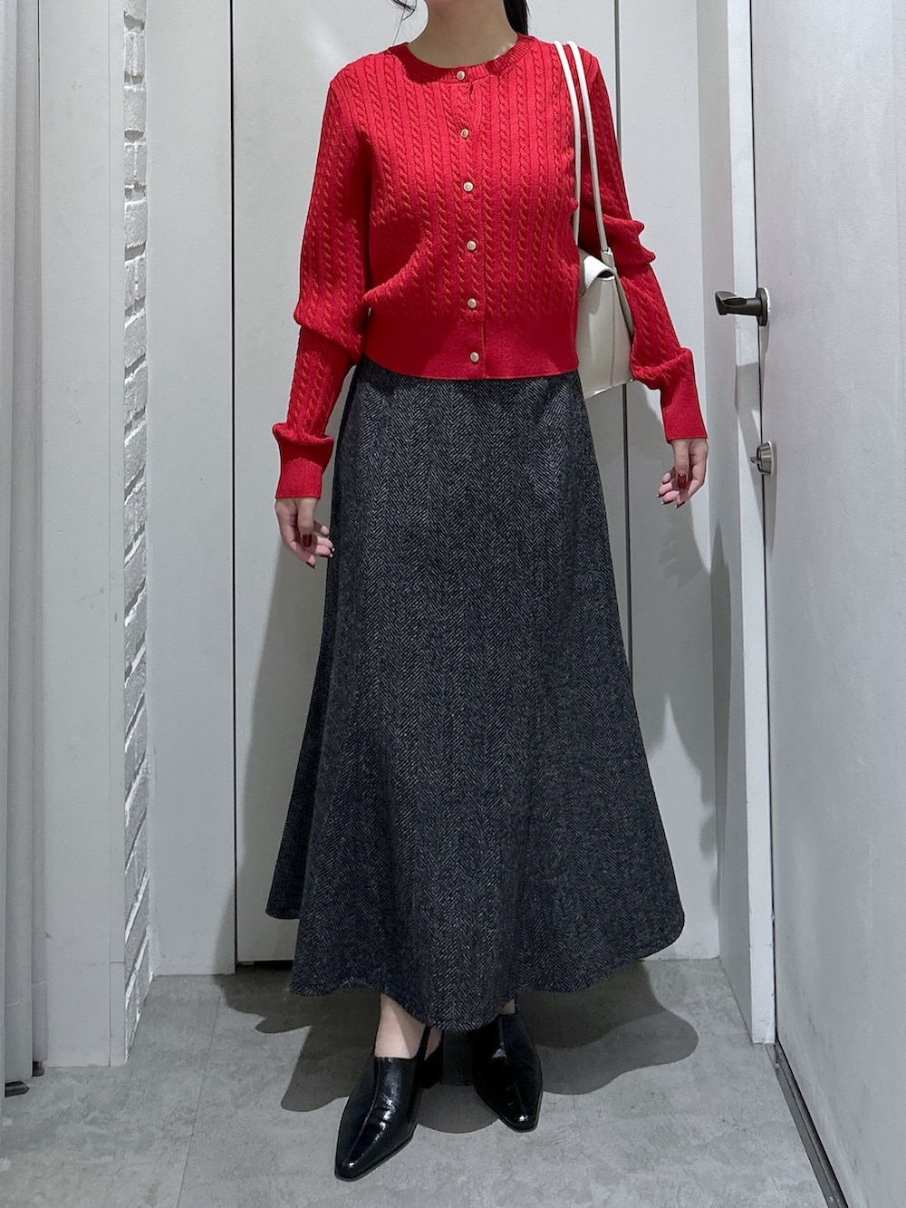 ブラック系のスカート、ホワイト系のショルダーバッグ、レッド系のニット/セーターを着用したレディースの冬コーディネートの3枚目の写真
