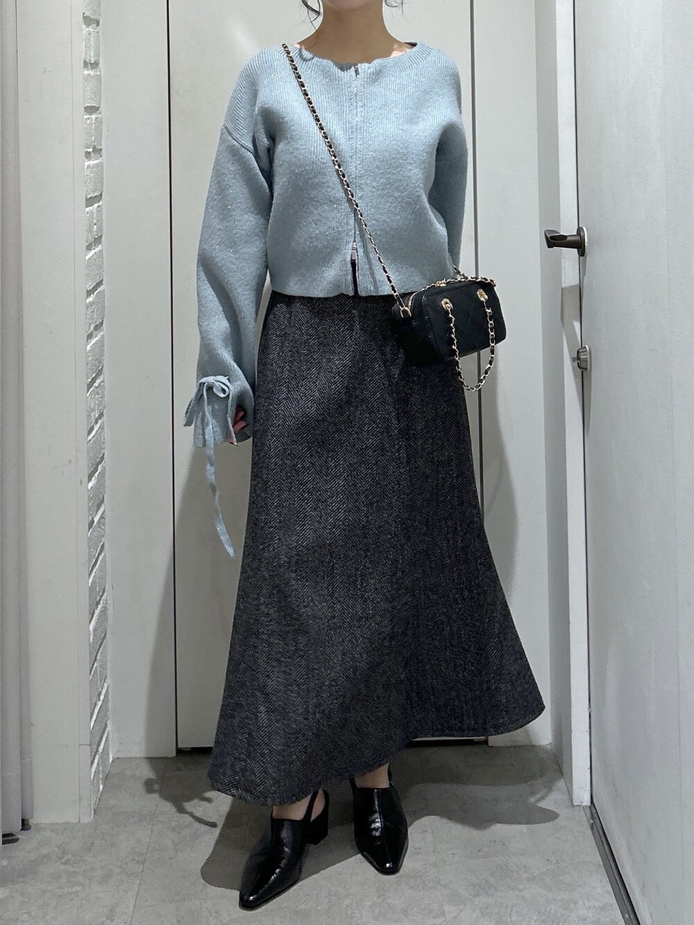 ブルー系のニット/セーター、ブラック系のスカート、ブラック系のパンプスを着用したレディースの冬コーディネートの3枚目の写真