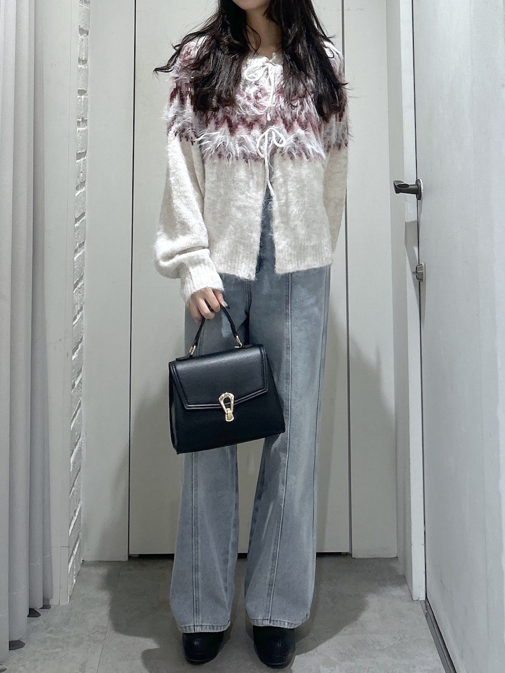 ホワイト系のニット/セーター、ブルー系のデニムパンツ、ブラック系のトートバッグを着用したレディースの秋コーディネートの2枚目の写真