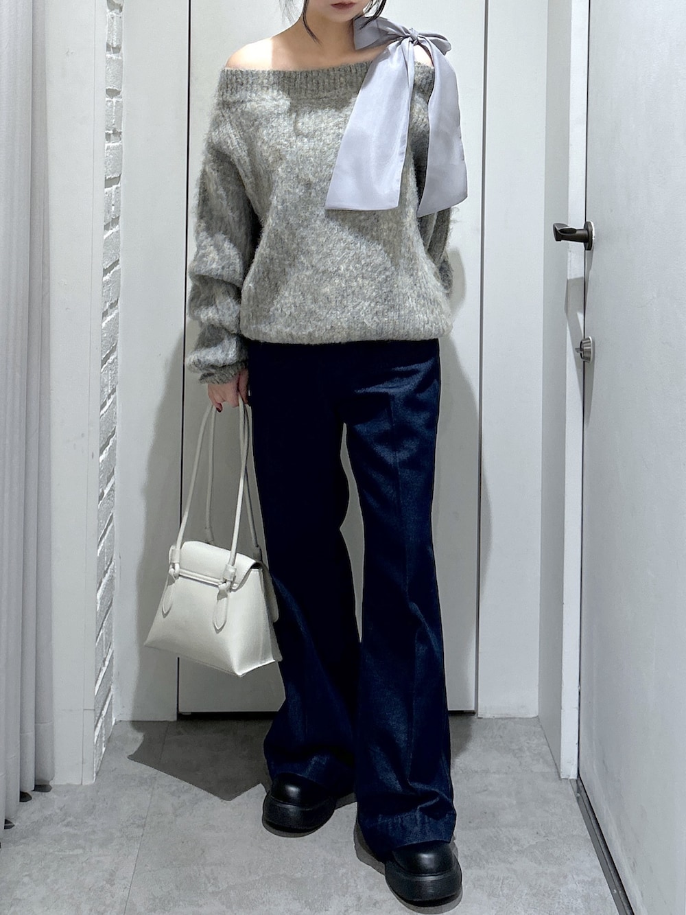 グレー系のニット/セーター、ブルー系のデニムパンツ、ホワイト系のショルダーバッグを着用したレディースの冬コーディネートの3枚目の写真