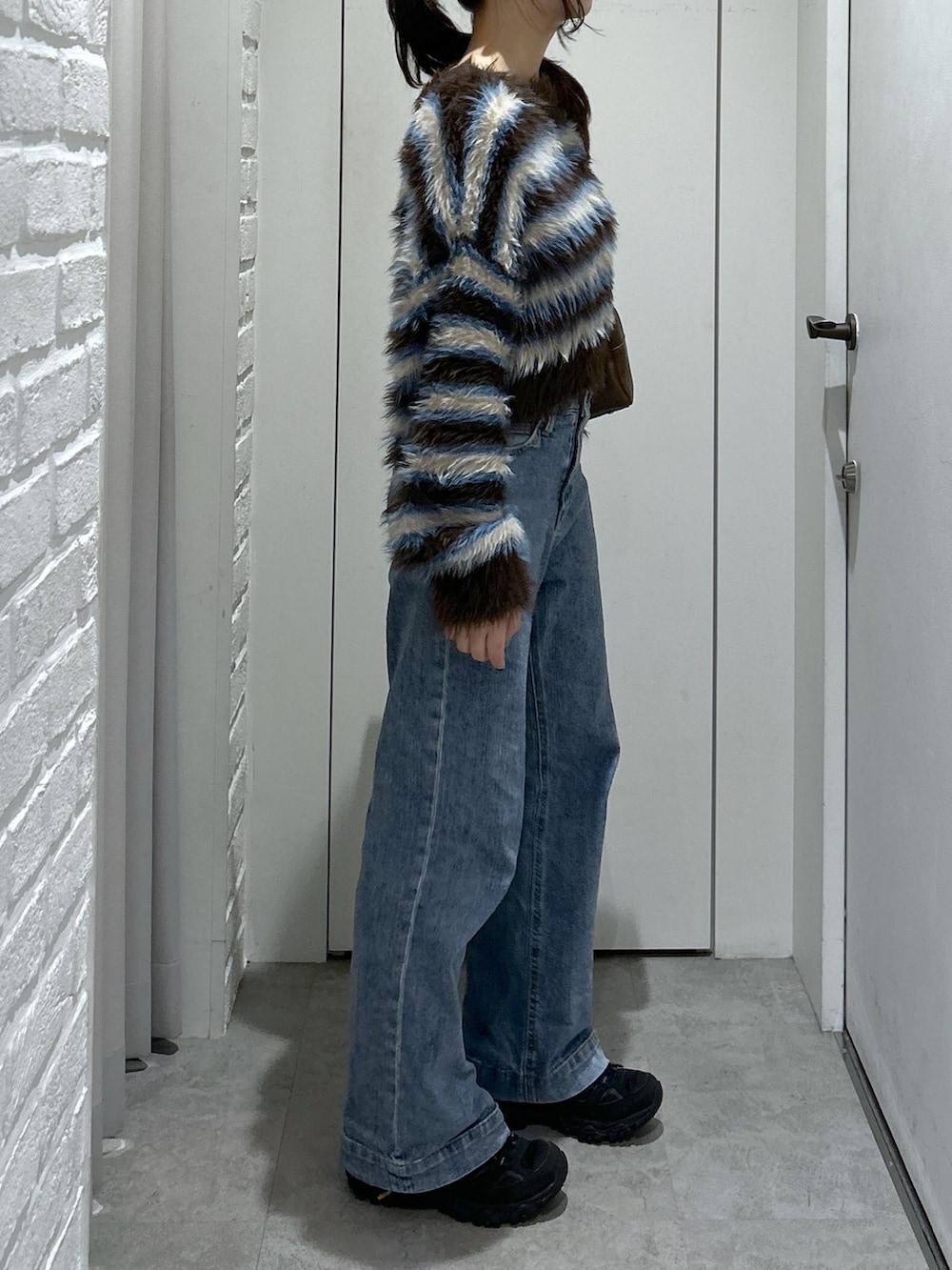 ブルー系のデニムパンツ、ブラウン系のトートバッグ、ブラウン系のニット/セーターを着用したレディースの秋コーディネートの4枚目の写真