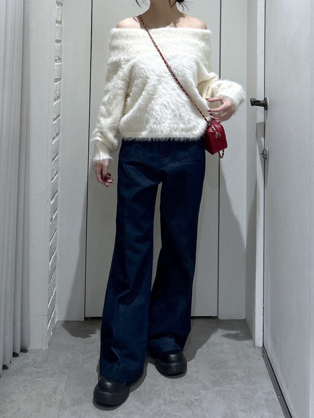 ブルー系のデニムパンツ、レッド系のショルダーバッグ、ホワイト系のニット/セーターを着用したレディースの冬コーディネートの3枚目の写真