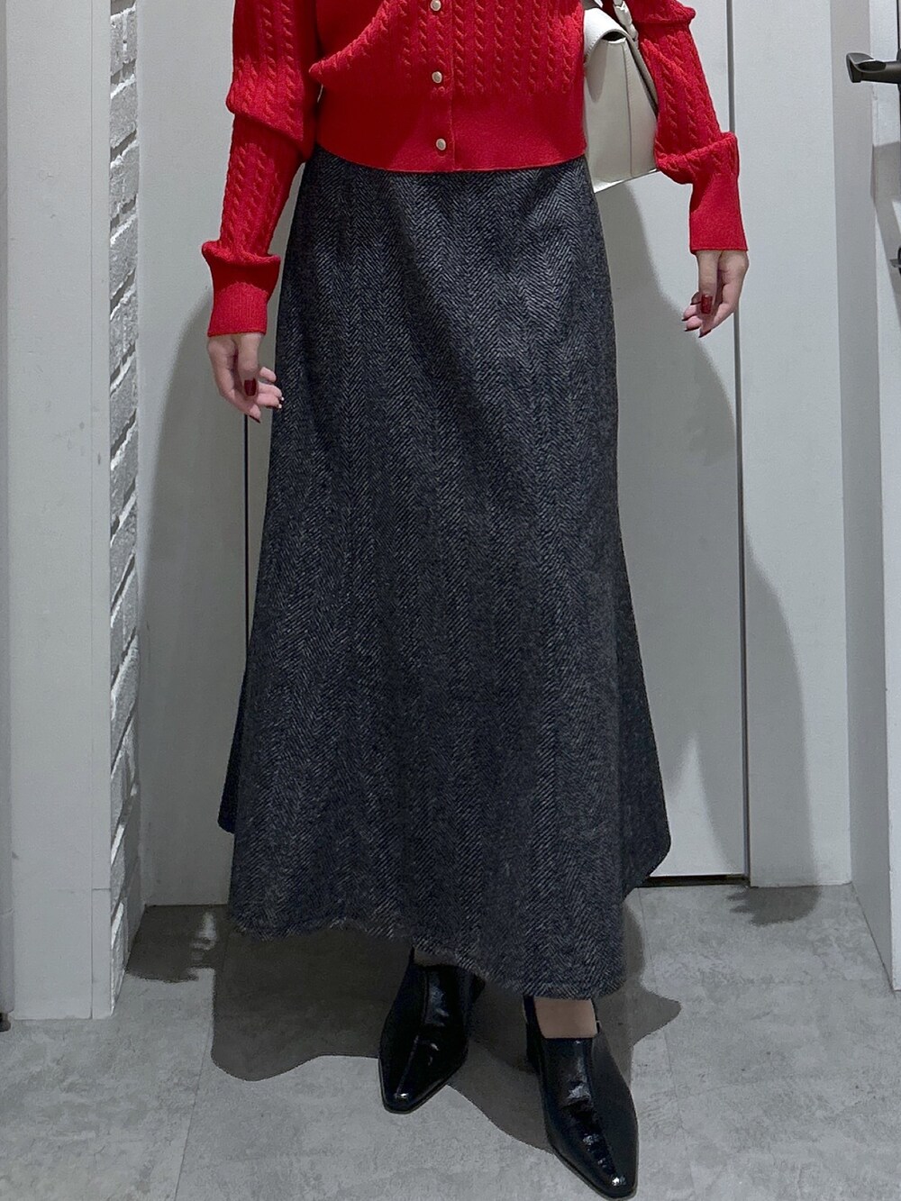 ブラック系のスカート、ホワイト系のショルダーバッグ、レッド系のニット/セーターを着用したレディースの冬コーディネートの4枚目の写真