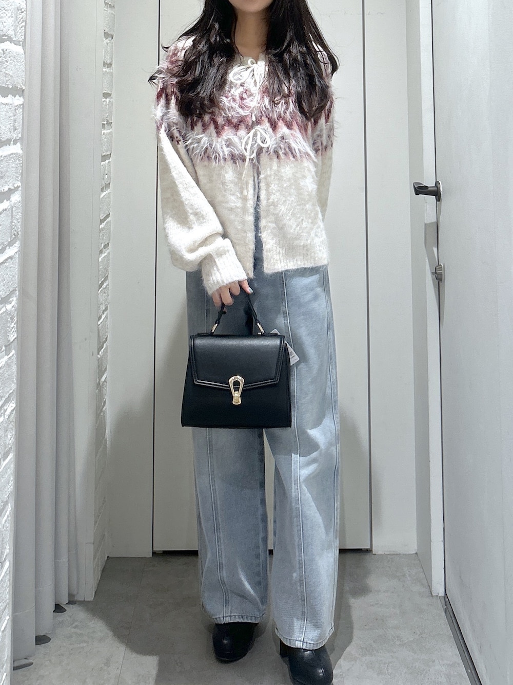 ホワイト系のニット/セーター、ブルー系のデニムパンツ、ブラック系のトートバッグを着用したレディースの秋コーディネートの3枚目の写真