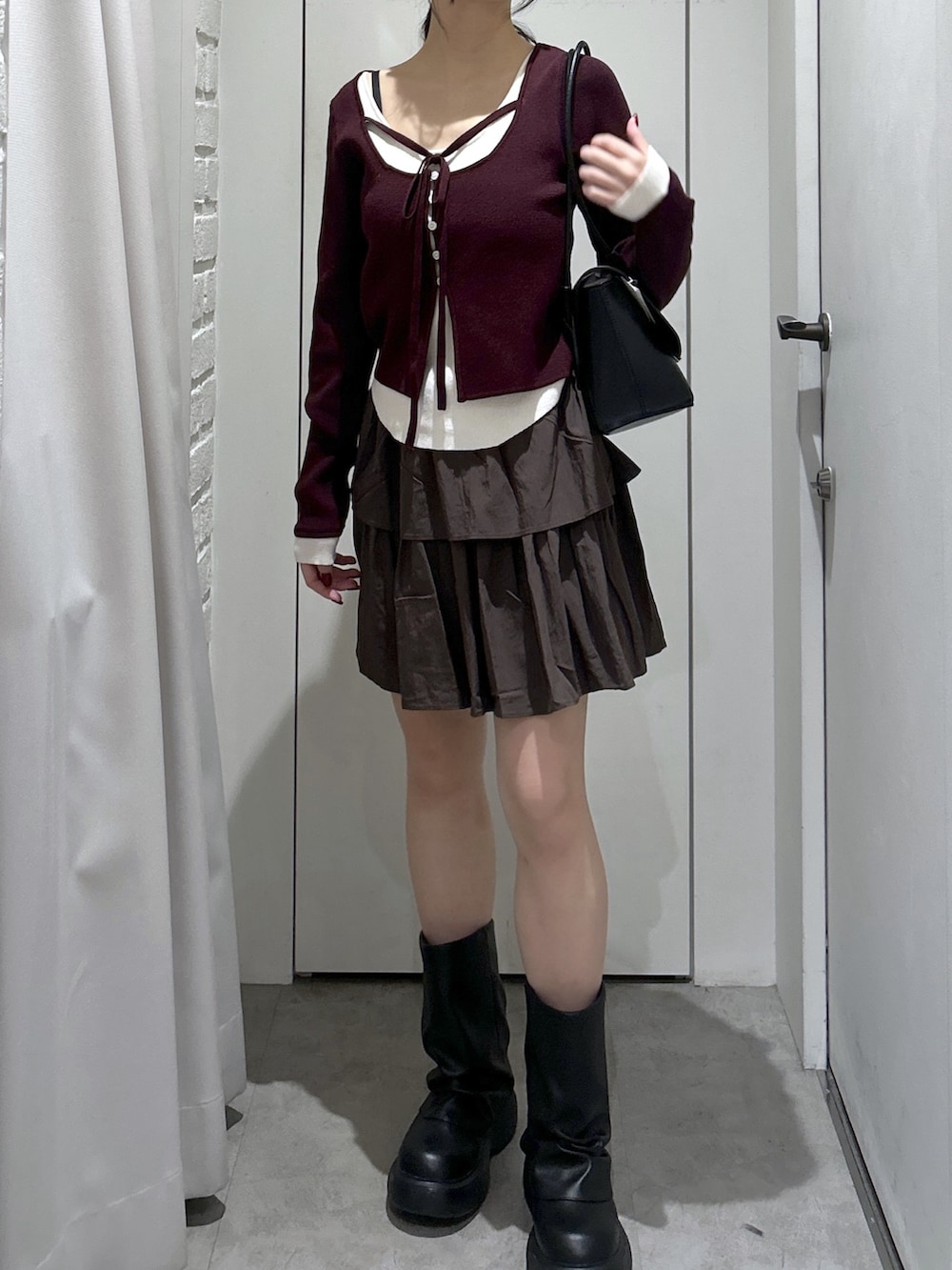 ブラウン系のスカート、ブラック系のショルダーバッグを着用したレディースの冬コーディネートの2枚目の写真