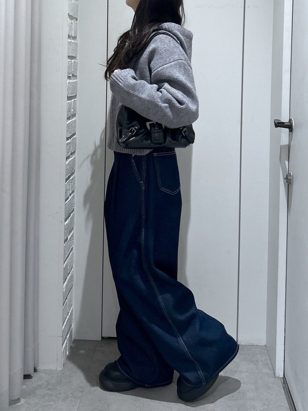 グレー系のニット/セーター、ブルー系のその他パンツ、ブラック系のショルダーバッグを着用したレディースの冬コーディネートの4枚目の写真