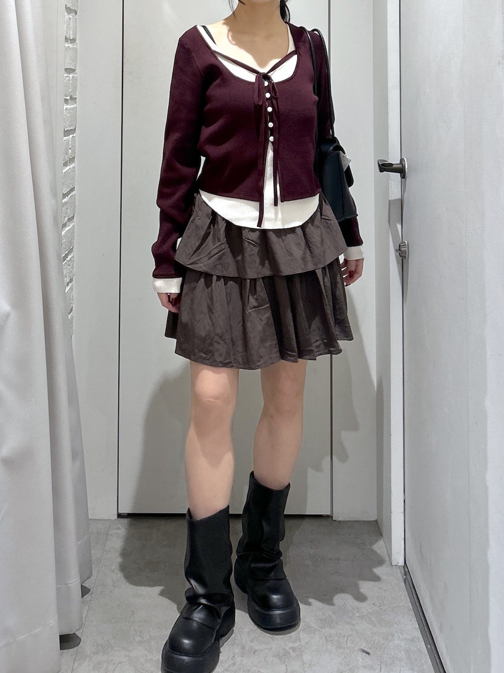 ブラウン系のスカート、ブラック系のショルダーバッグを着用したレディースの冬コーディネートの3枚目の写真