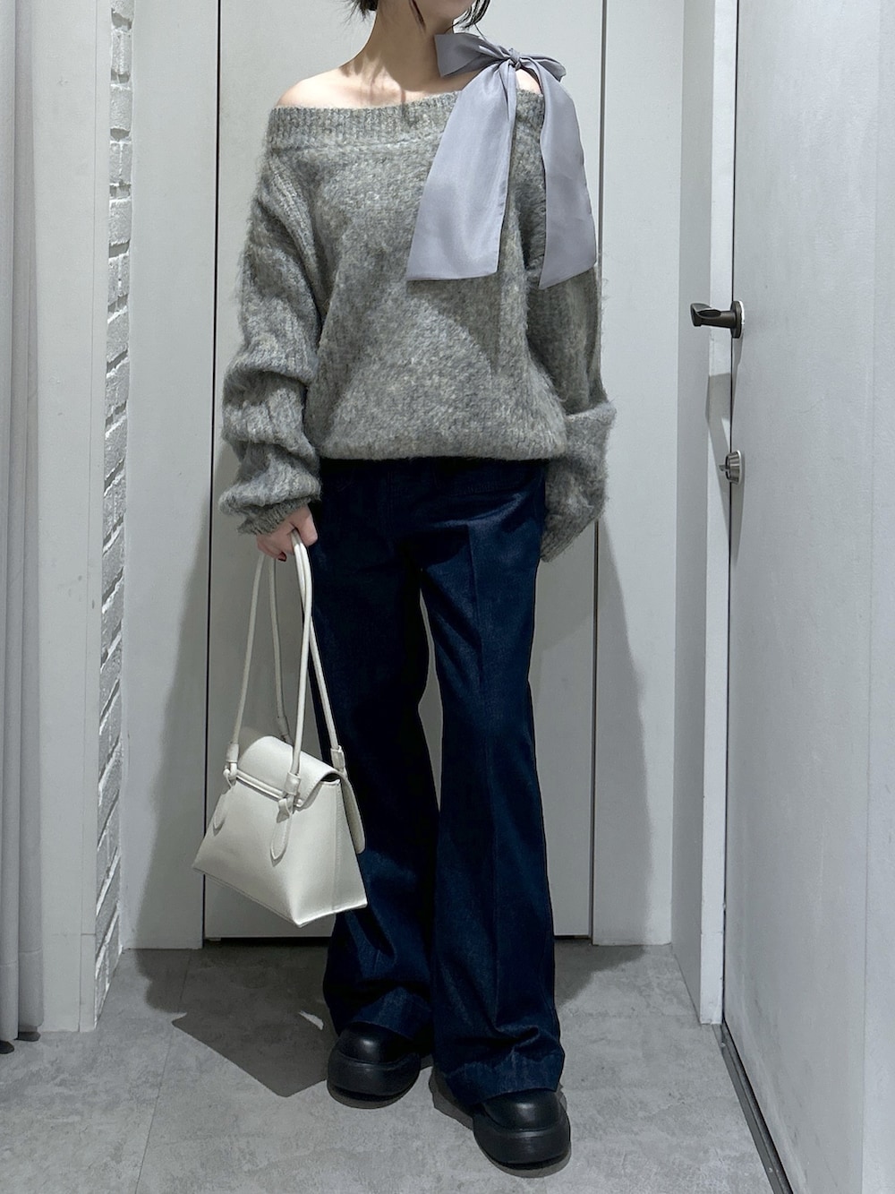 グレー系のニット/セーター、ブルー系のデニムパンツ、ホワイト系のショルダーバッグを着用したレディースの冬コーディネートの4枚目の写真