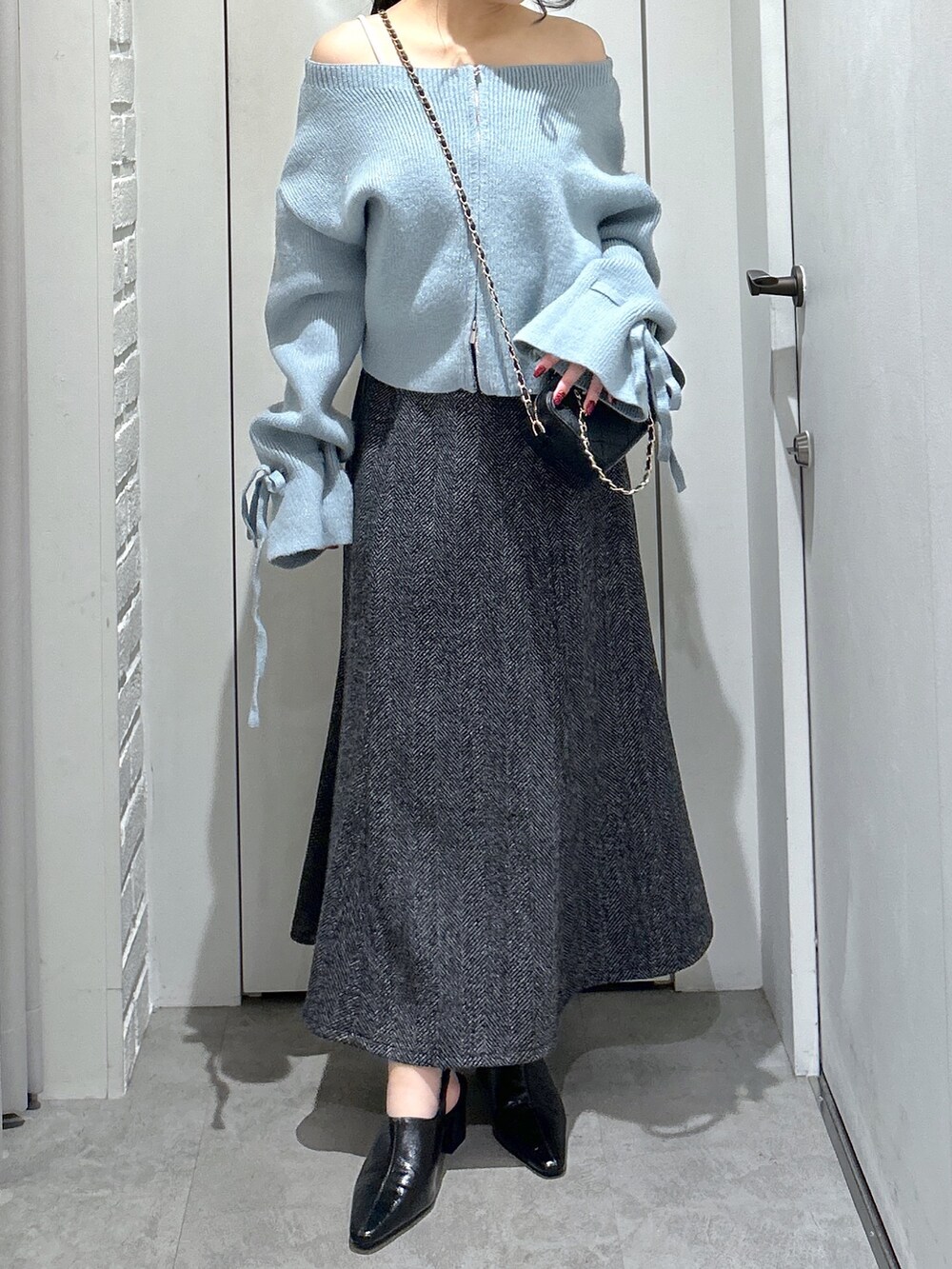 ブルー系のニット/セーター、ブラック系のスカート、ブラック系のパンプスを着用したレディースの冬コーディネートの5枚目の写真