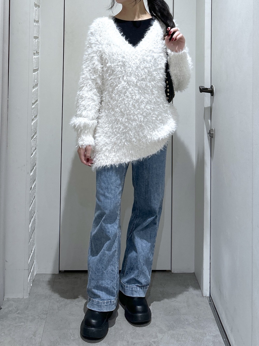 ホワイト系のニット/セーター、ブラック系のショルダーバッグ、ブルー系のデニムパンツを着用したレディースの冬コーディネートの4枚目の写真