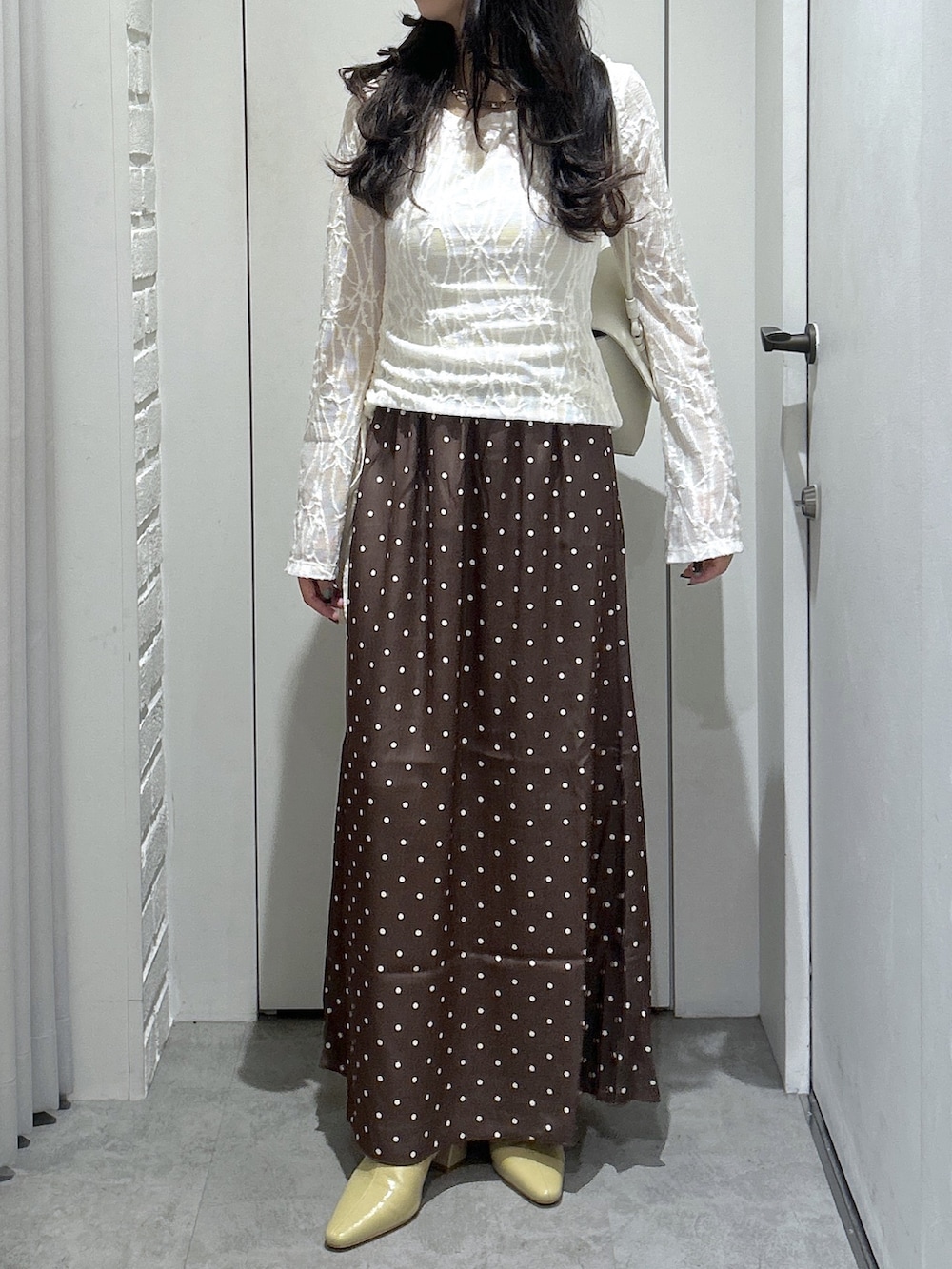 ホワイト系のショルダーバッグ、ホワイト系のTシャツ/カットソー、ベージュ系のパンプスを着用したレディースの秋コーディネートの2枚目の写真