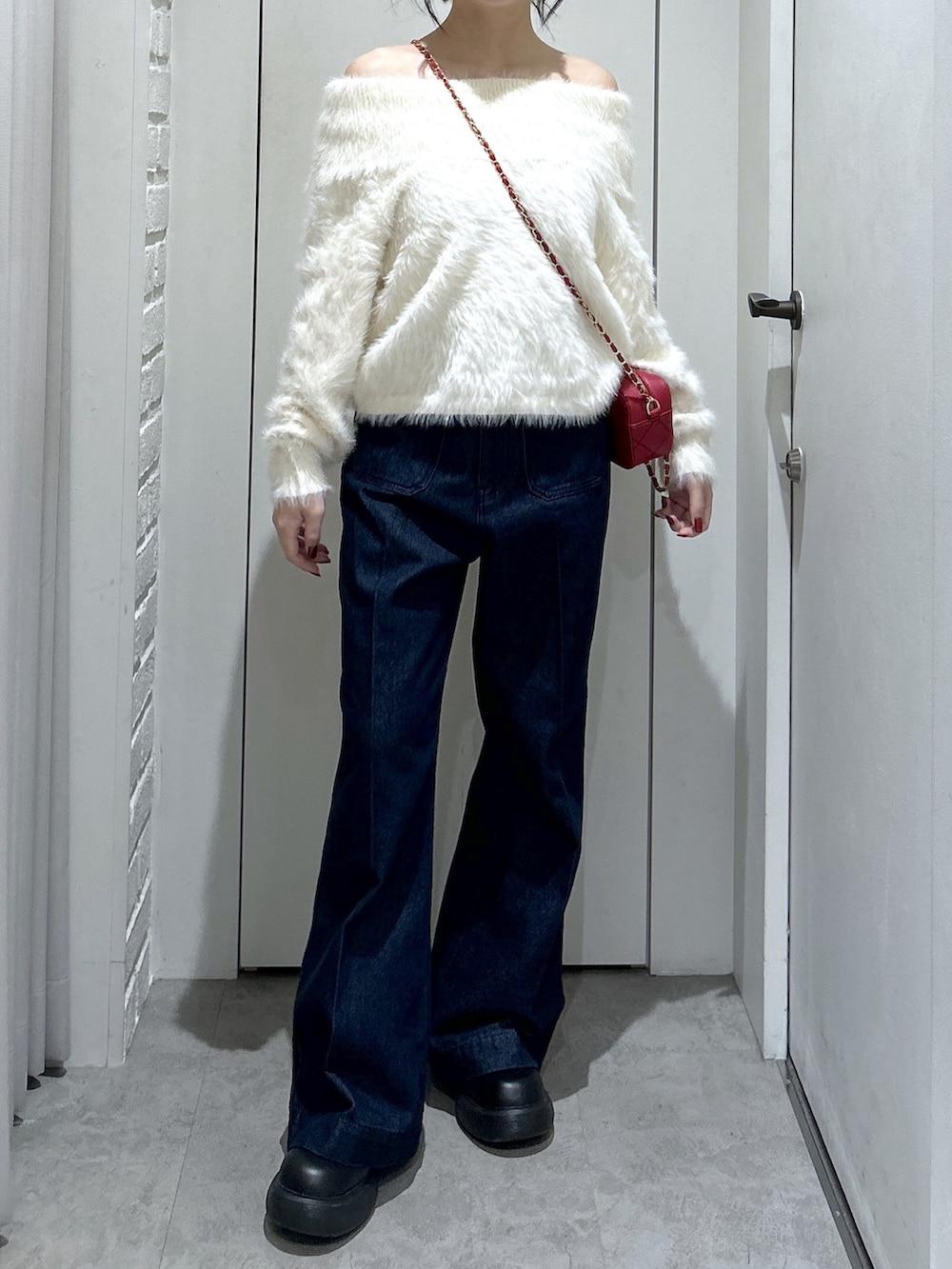 ブルー系のデニムパンツ、レッド系のショルダーバッグ、ホワイト系のニット/セーターを着用したレディースの冬コーディネートの4枚目の写真