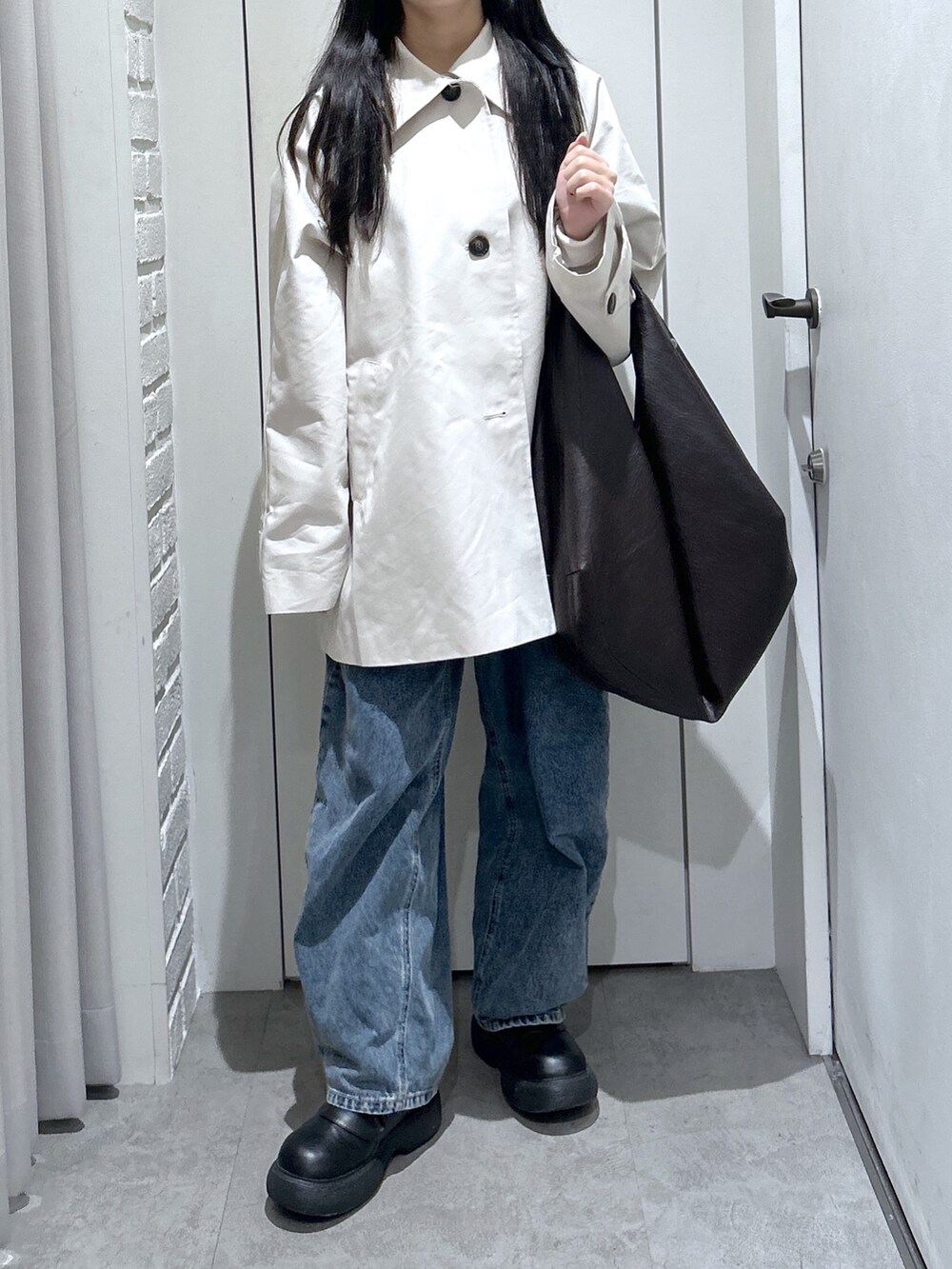 ブラウン系のトートバッグ、ホワイト系のニット/セーター、ブルー系のデニムパンツを着用したレディースの春コーディネートの3枚目の写真