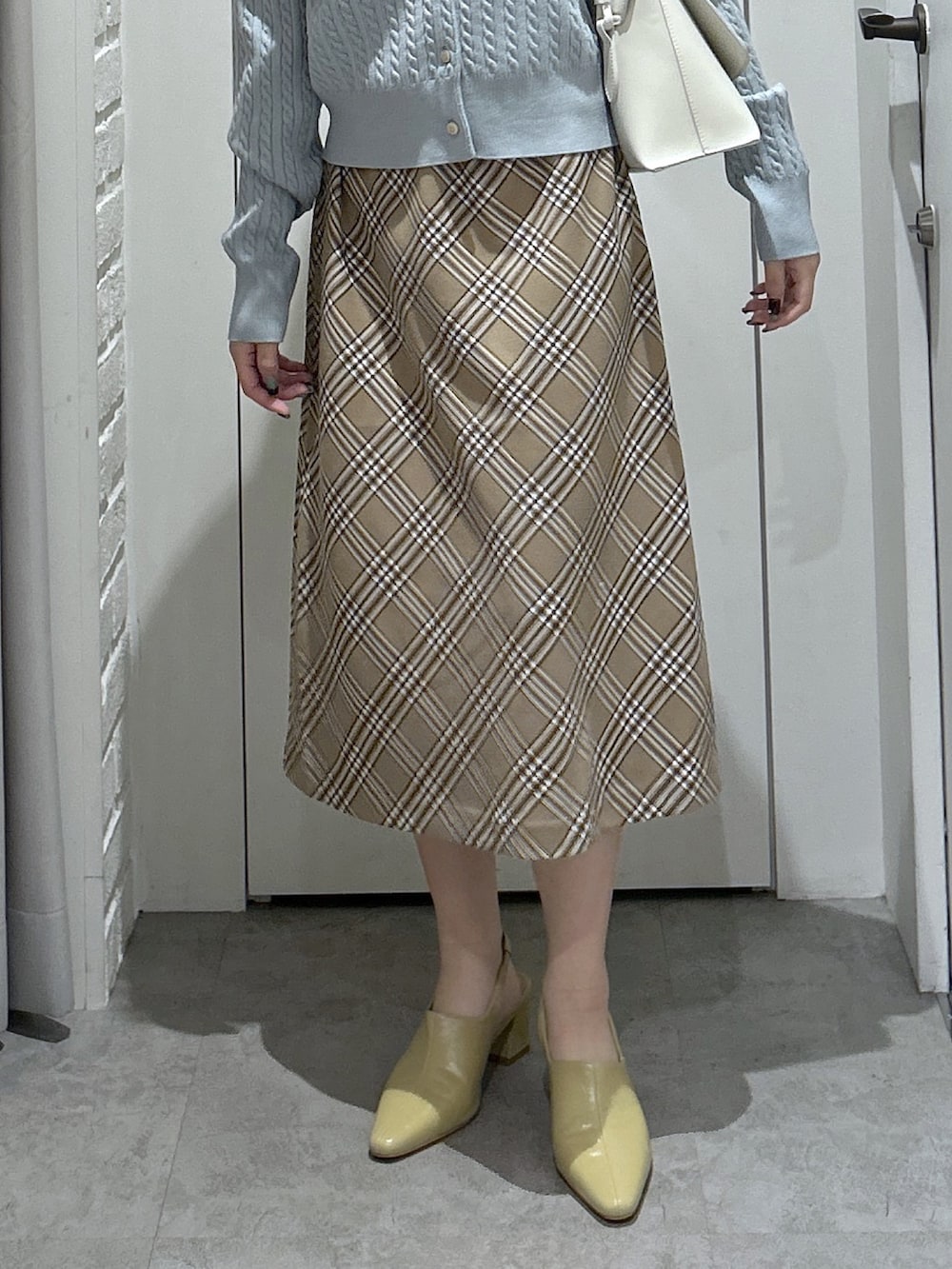 ブルー系のカーディガン/ボレロ、ベージュ系のスカート、ホワイト系のトートバッグを着用したレディースの秋コーディネートの5枚目の写真