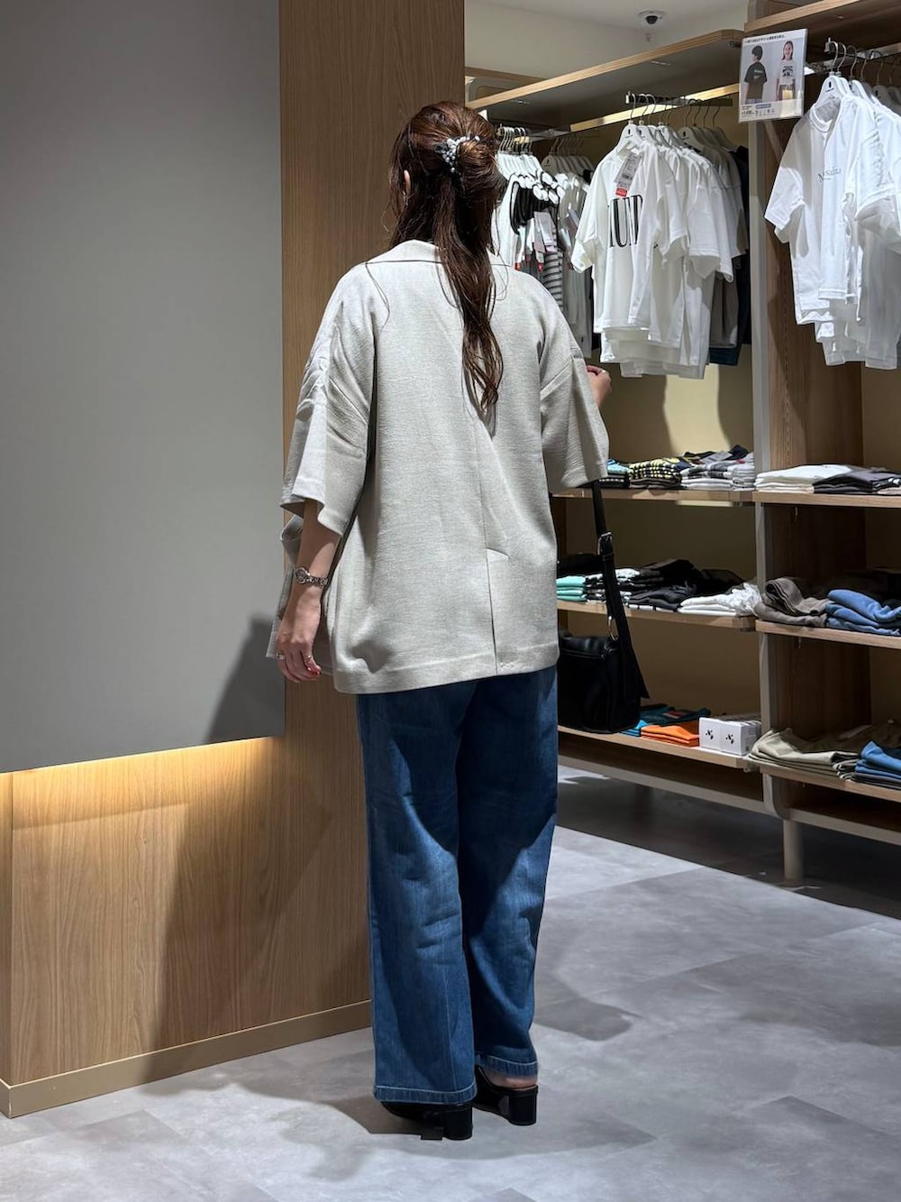 ブルー系のデニムパンツ、ベージュ系のテーラードジャケット、ブラック系のサンダルを着用したレディースの夏コーディネートの4枚目の写真